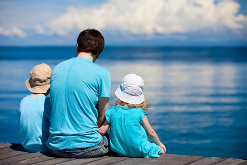 Father and kids sitting on wooden dock