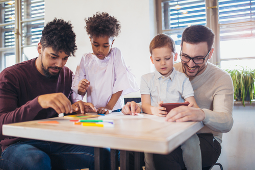 Two fathers play educational games with their children,