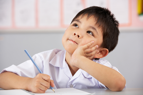 Male Student Working At Desk In Chinese School Classroom