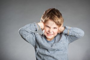 Portrait of boy, hear no evil, grey background