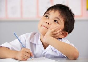 Male Student Working At Desk In Chinese School Classroom