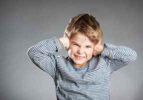 Portrait of boy, hear no evil, grey background