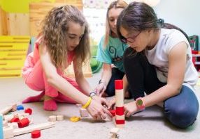 Two girls playing together with wooden toy blocks