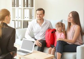Young couple and their daughter meeting with headmistress at school parent and teacher with child
