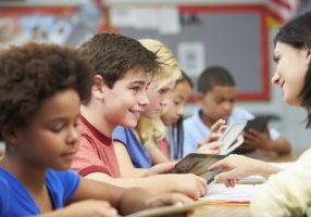 Pupils In Class Using Digital Tablet With Teacher